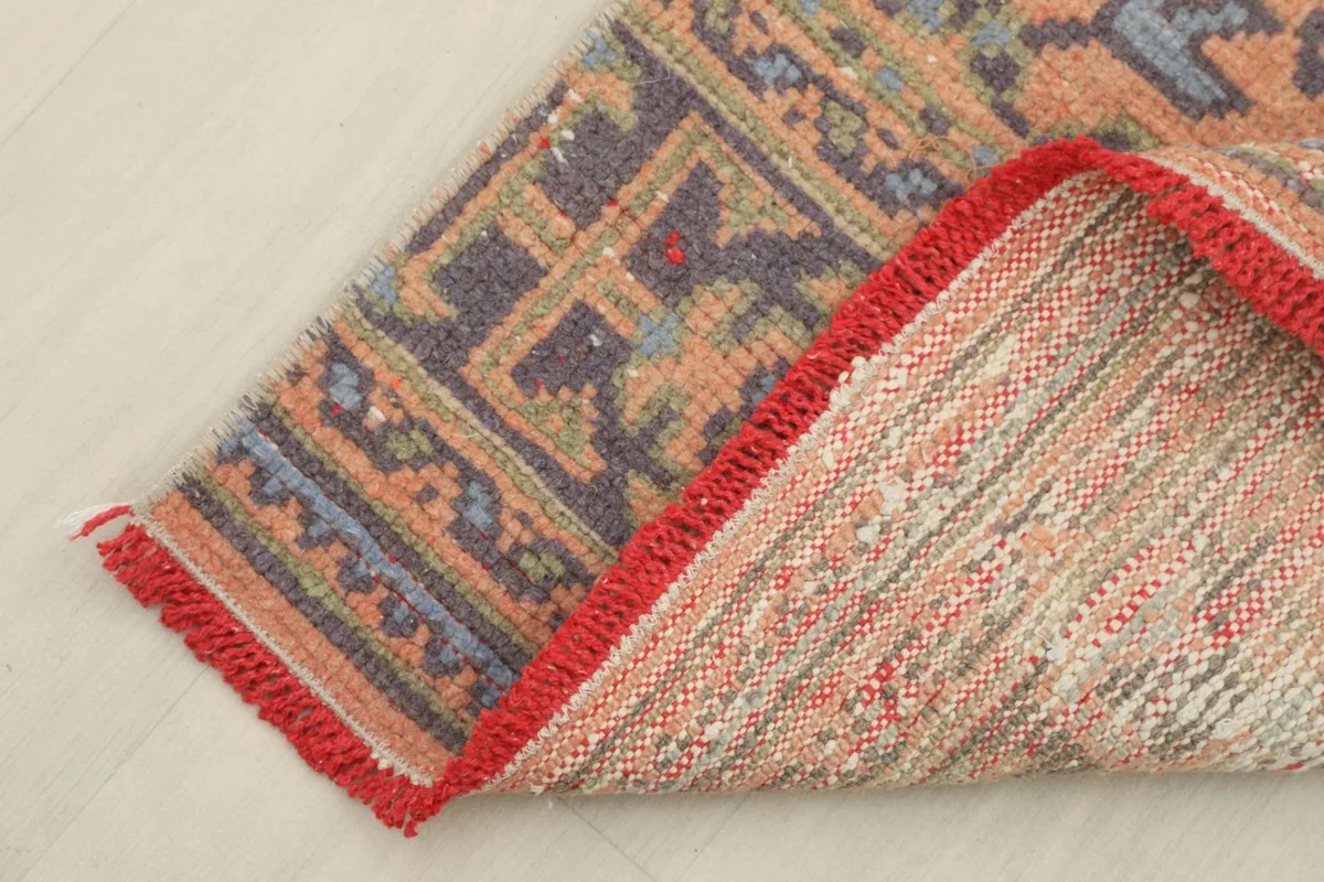 Corner of the runner rug folded to show the cotton foundation and hand-knotted construction