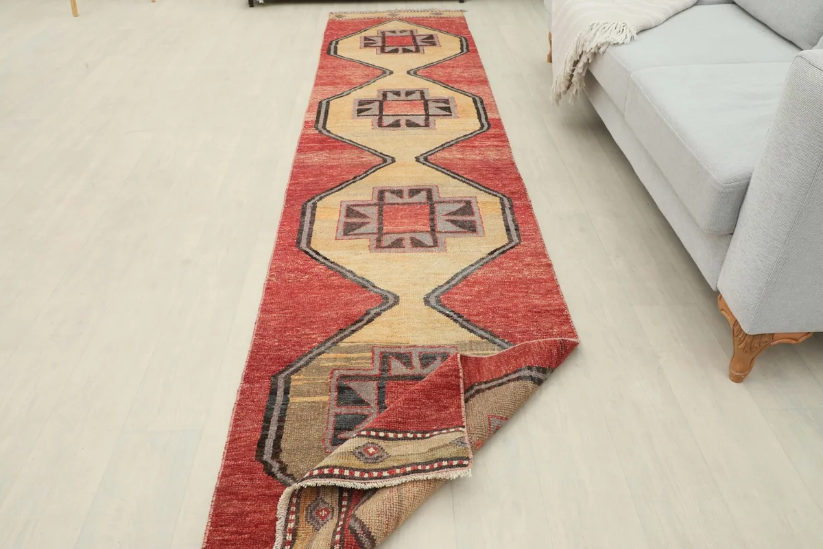 Long view of the runner rug in a room setting, partially folded to display its length and design.