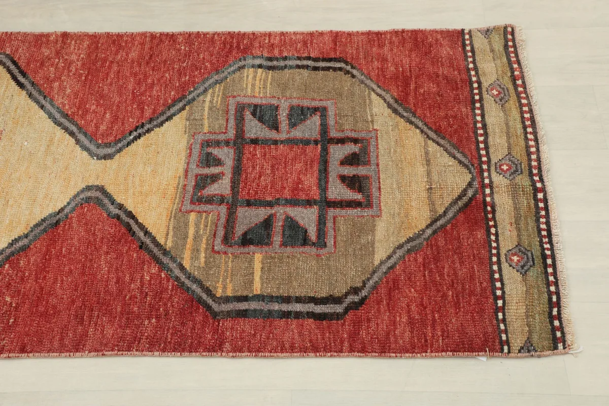 Close-up view of a central beige diamond motif with red, gray, and black geometric designs.