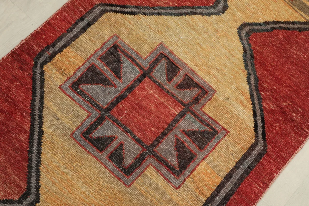 Detailed overhead shot of a beige geometric motif with a red center and black and gray accents.