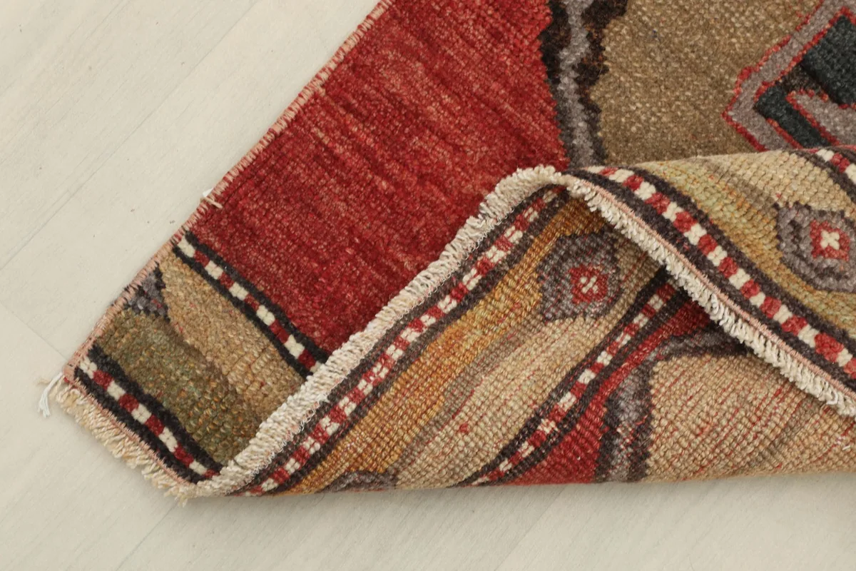 Corner of the rug folded to show the wool pile and cotton foundation, with visible fringes.