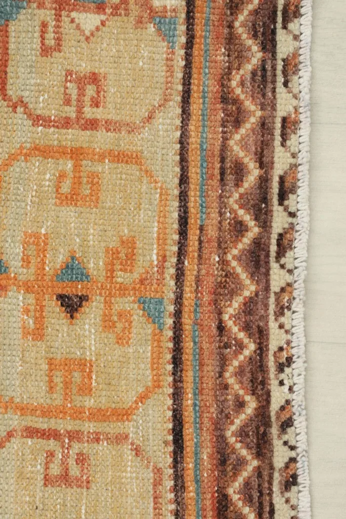 Close-up of the rug's side border, showing the brown zigzag pattern and colors