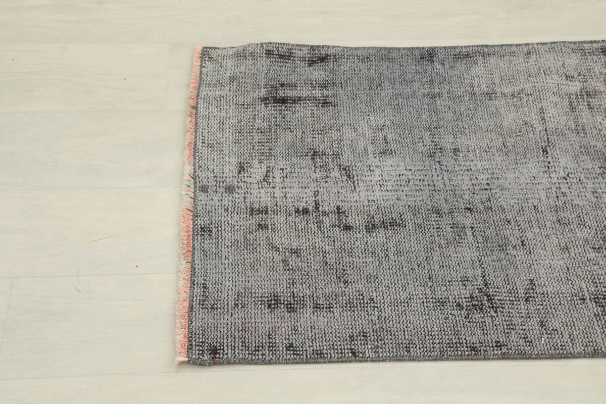 Detailed angle view of the rug's surface, highlighting the faded charcoal and gray tones
