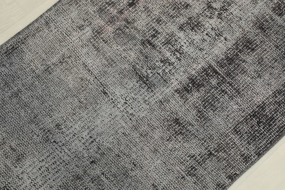 Close-up detail of the hand-knotted wool pile, showing the distressed geometric patterns