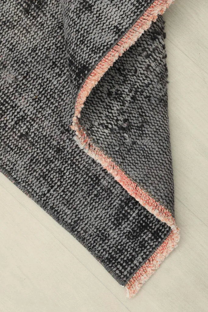 Corner of the rug folded to show the thickness and the back of the hand-knotted cotton foundation