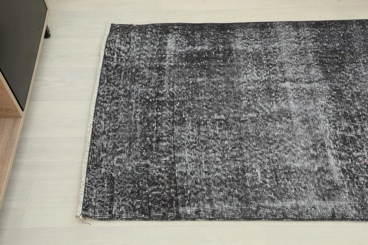 Another angled view of the rug's texture and color variation, highlighting its worn character.