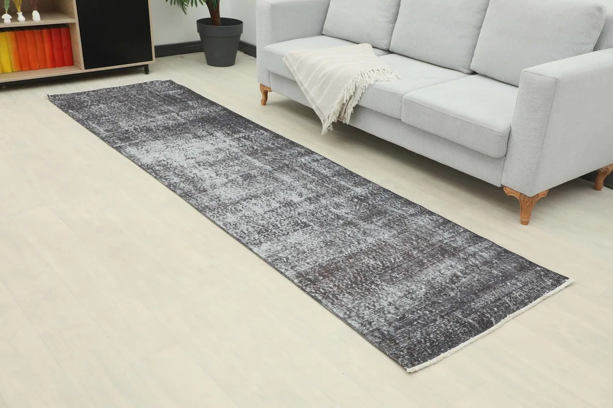 Angled view of the vintage runner rug extending along a wall next to a sofa in a room.