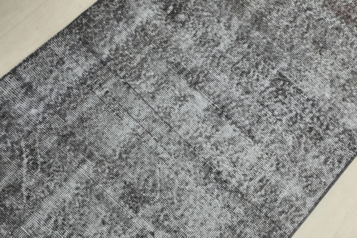 Detailed view of the rug's pile, revealing the subtle geometric patterns and variations in charcoal and gray.