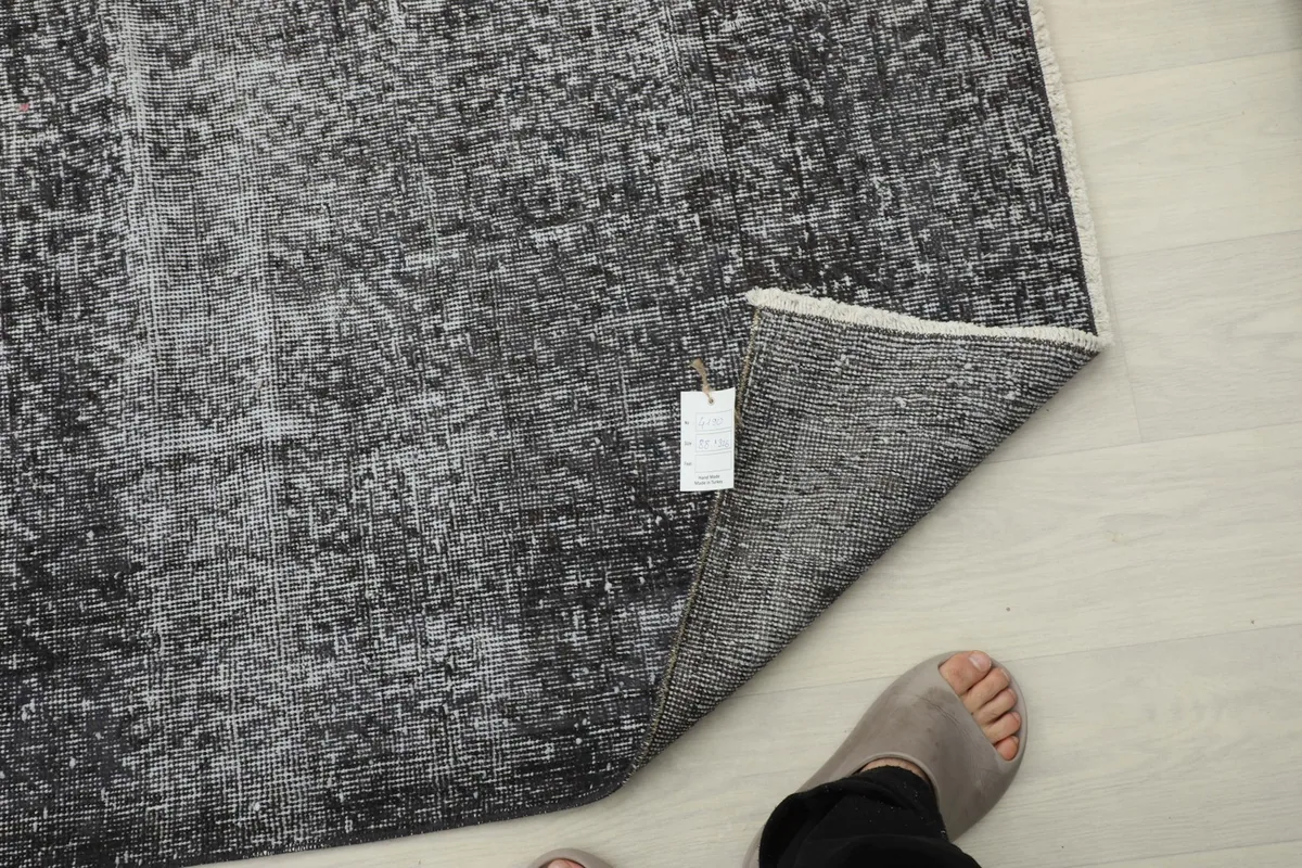 Close-up of the rug's back and foundation, with a product tag visible near a foot.