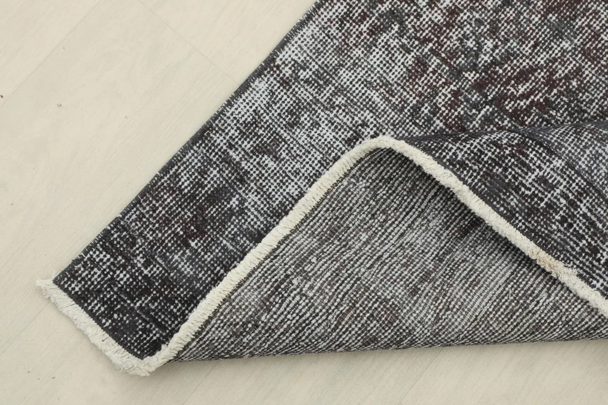 Corner of the rug folded back, showing the cotton foundation and the reverse side.
