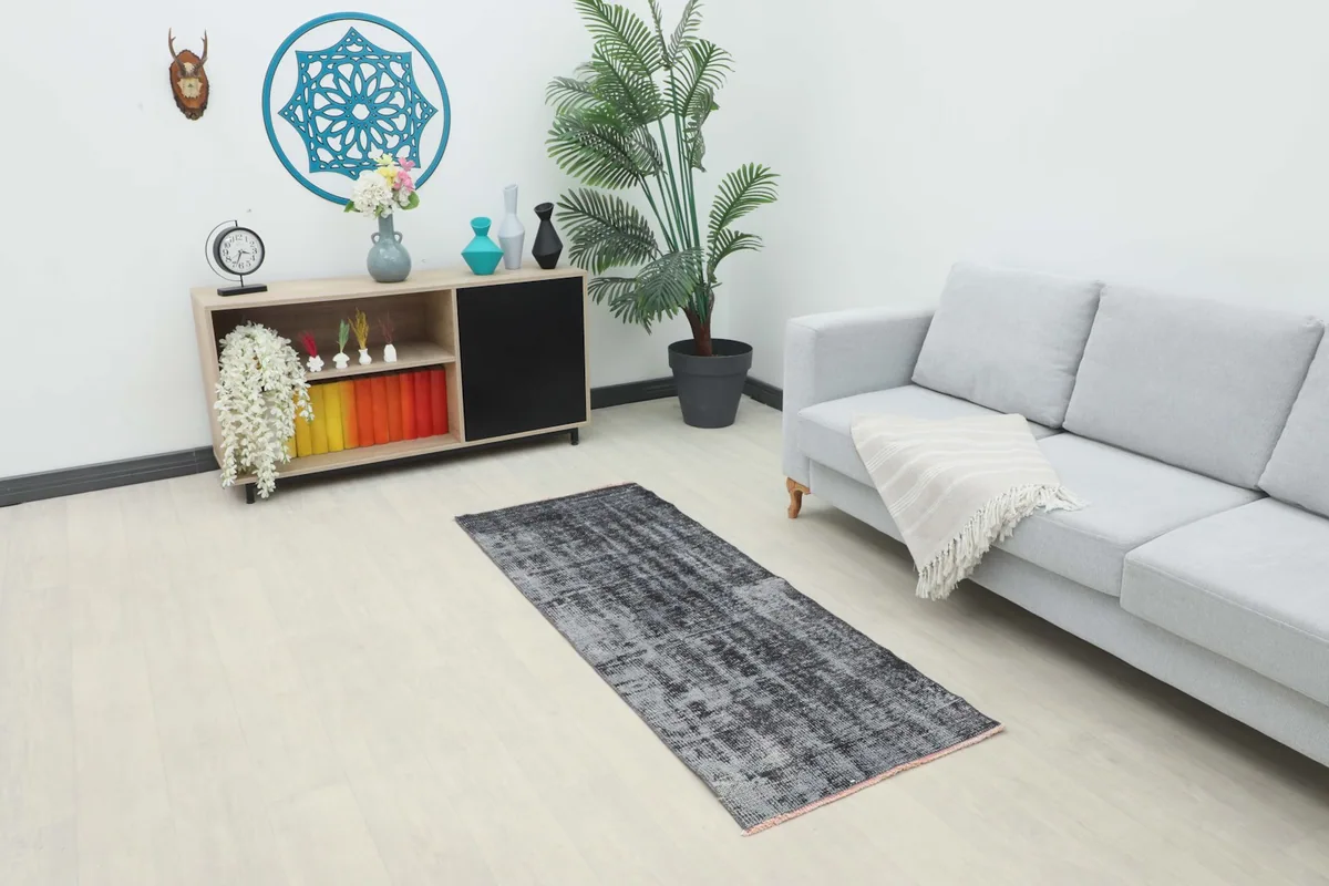 Charcoal gray runner rug in a modern living room setting with a light gray sofa and wooden cabinet
