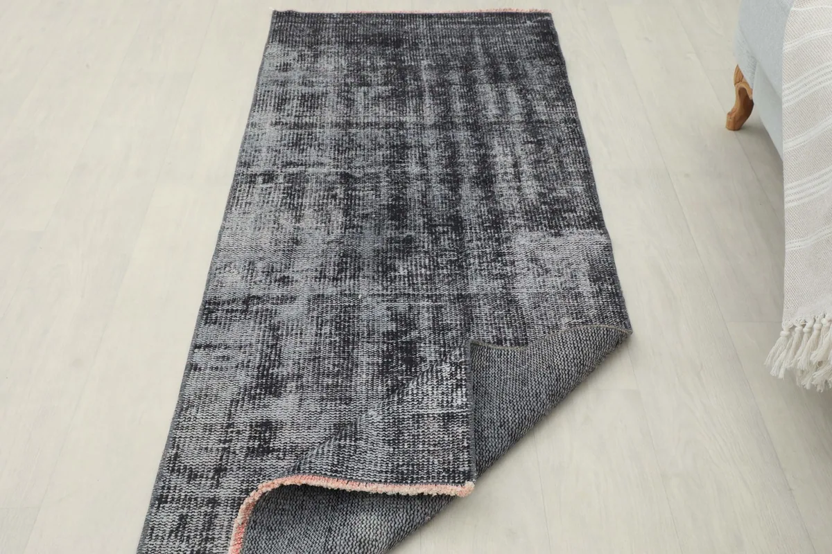 Partial view of the back of the runner rug, revealing the hand-knotted cotton foundation