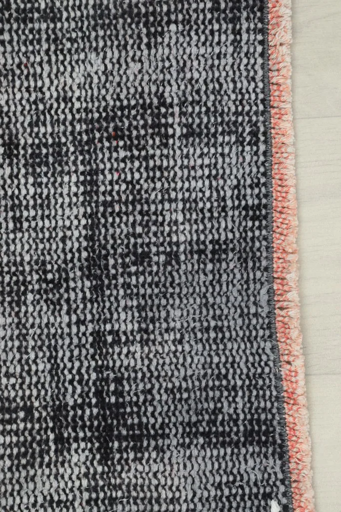 Detail view of the short, subtle fringe and the side binding of the charcoal gray runner rug