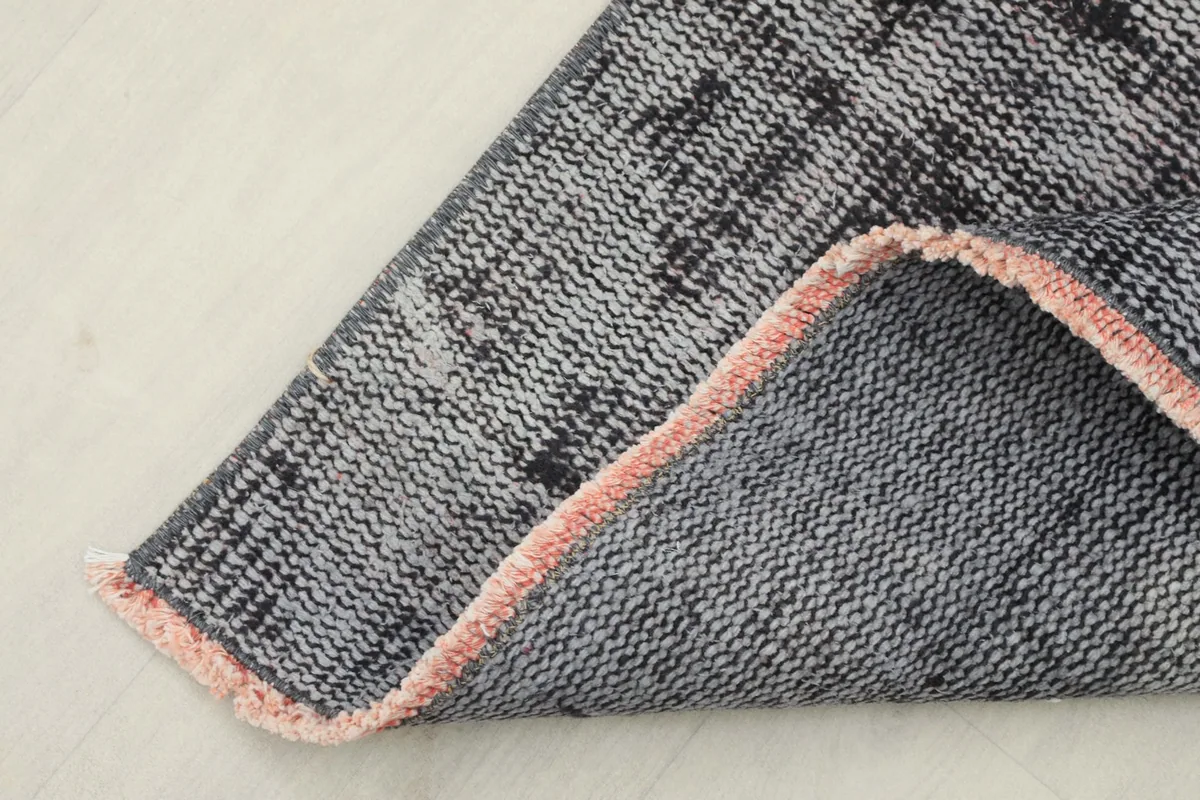 Corner of the runner rug folded back, showing the cotton foundation and the reverse side