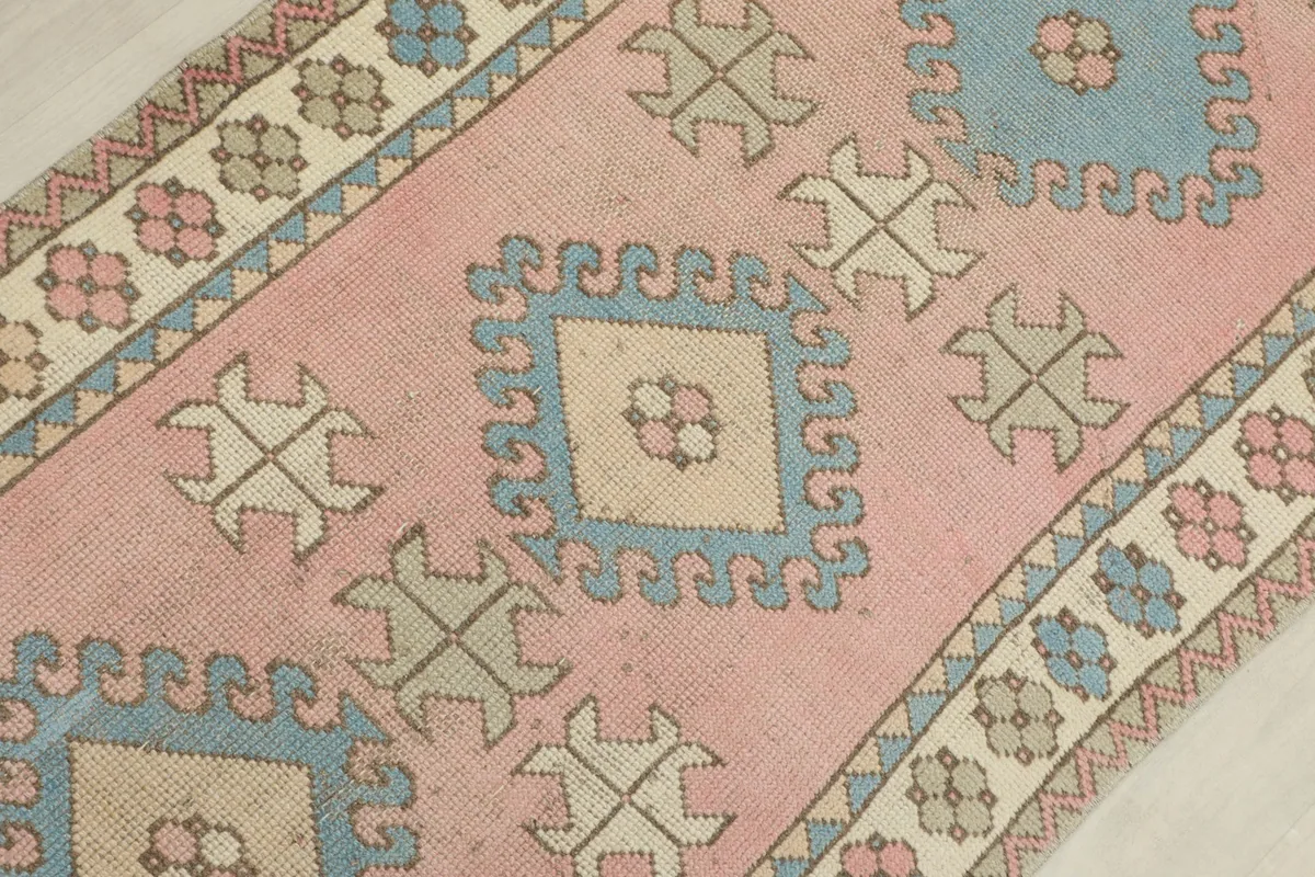 Detailed view of the runner's central design, featuring a pink field with blue and beige diamond motifs