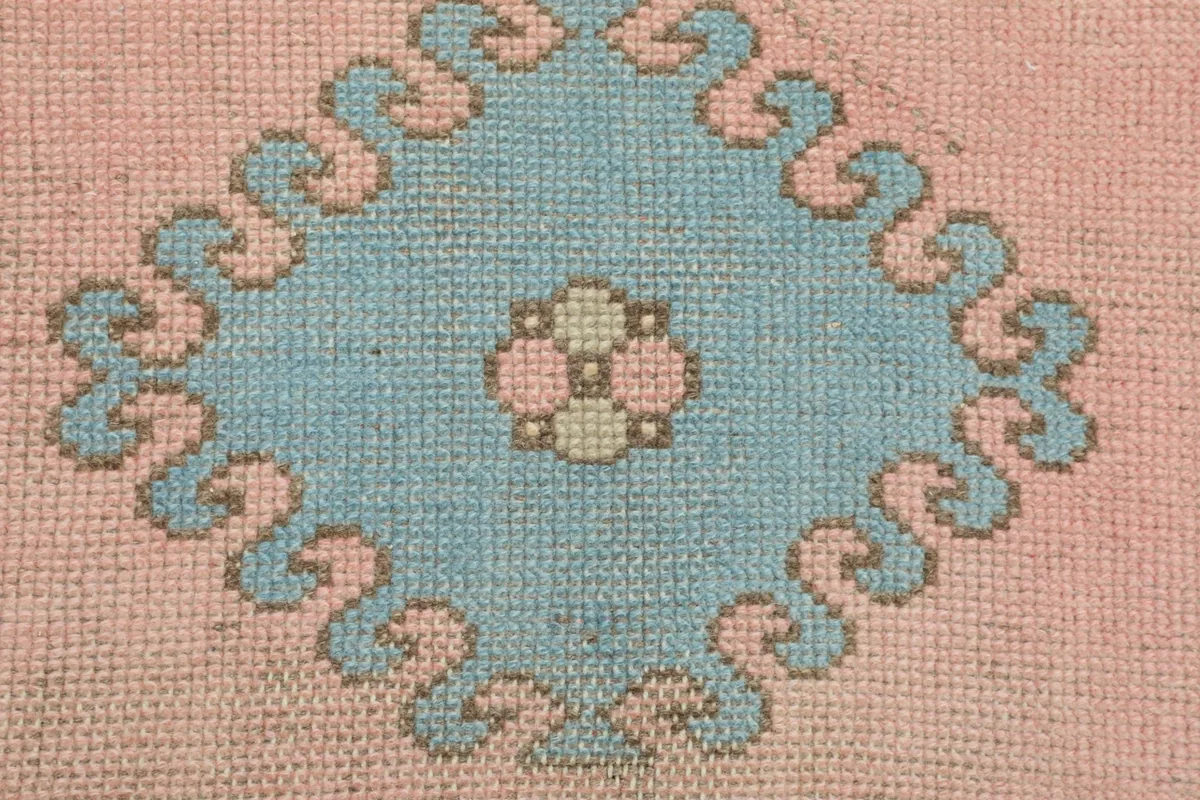 Close-up of a central blue geometric diamond motif with a small floral element in the middle