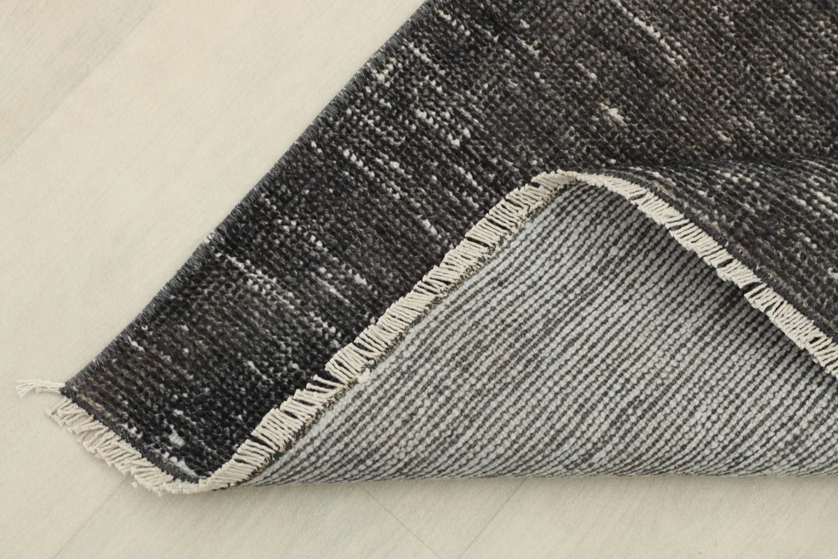 Corner of the runner rug folded to show the cotton foundation on the reverse side