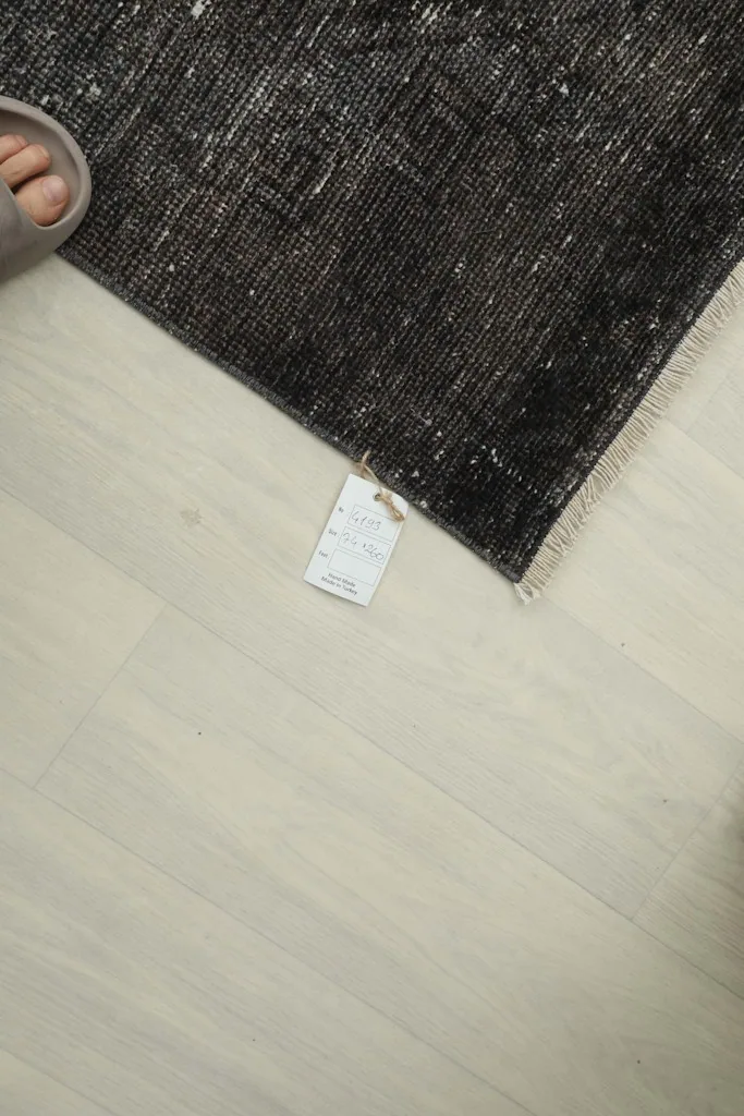 Corner of the runner rug with a product tag and a person's foot nearby for scale