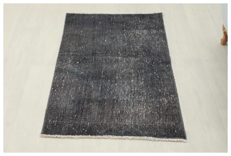 Full top view of the charcoal and gray vintage Anatolian rug on a white floor