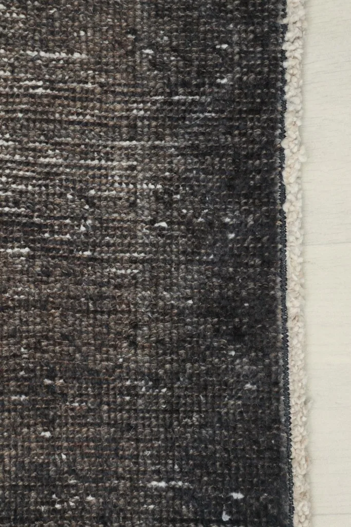 Detail of the rug's edge, showing the finished side and a hint of the cotton foundation