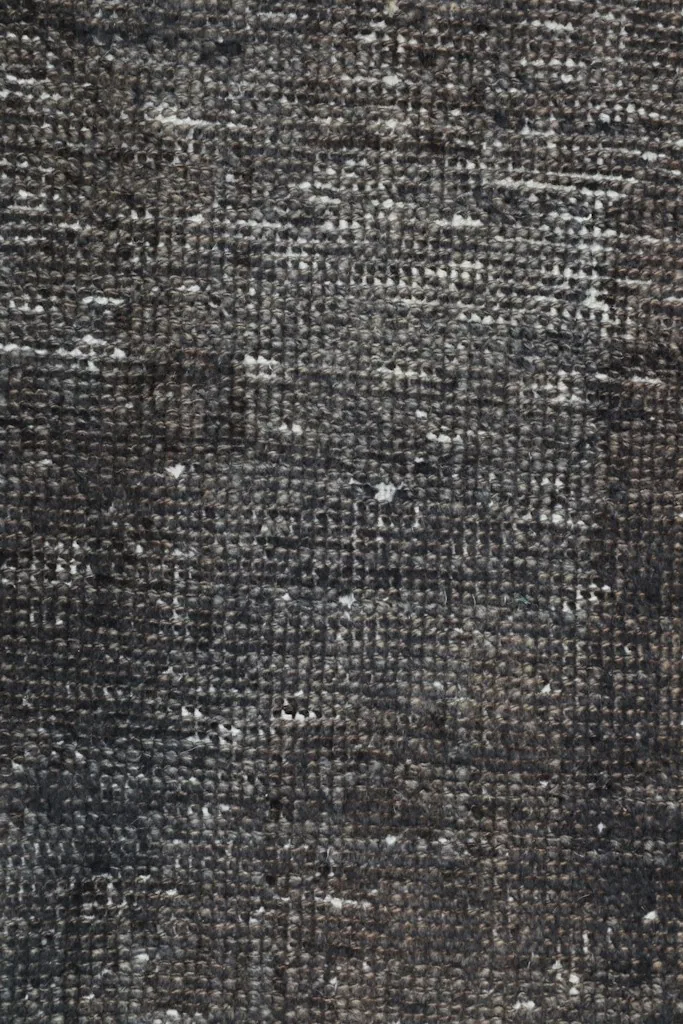 Close-up of the hand-knotted wool pile, showing individual knots and distressed areas