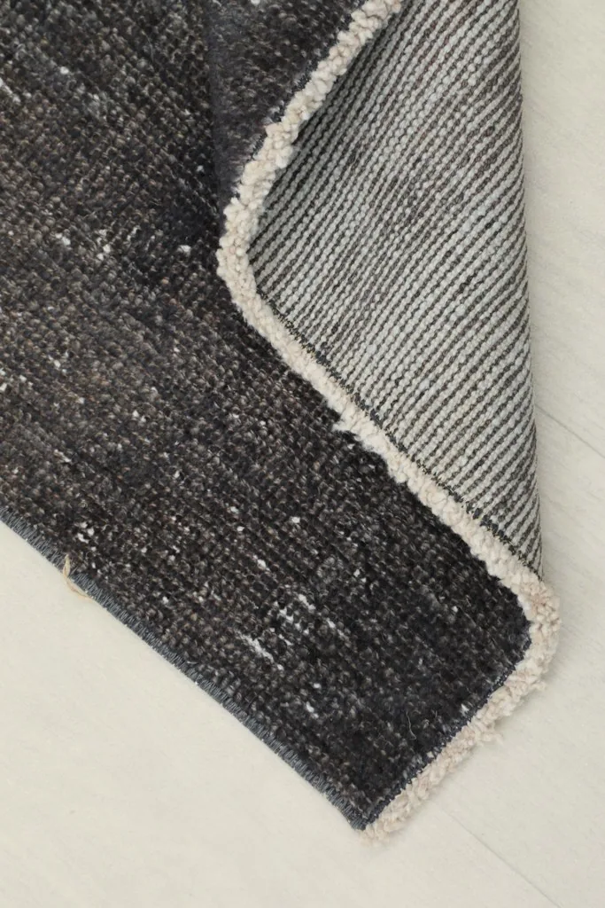 Corner of the rug folded to reveal the cotton foundation and hand-knotted construction