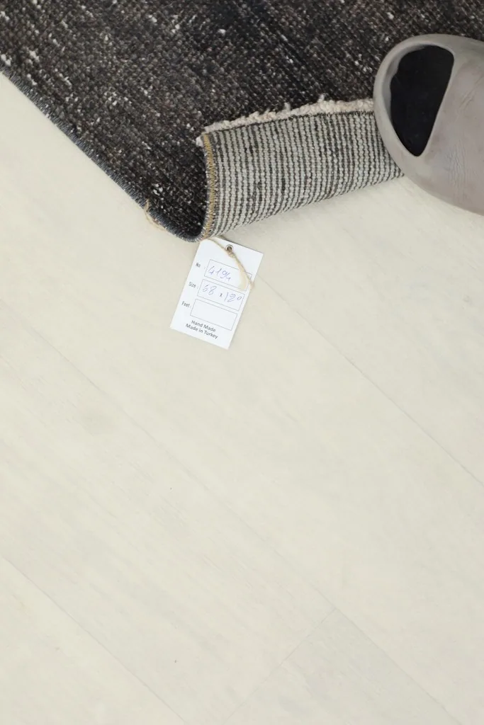 Product tag attached to the rug, with a slipper nearby for scale