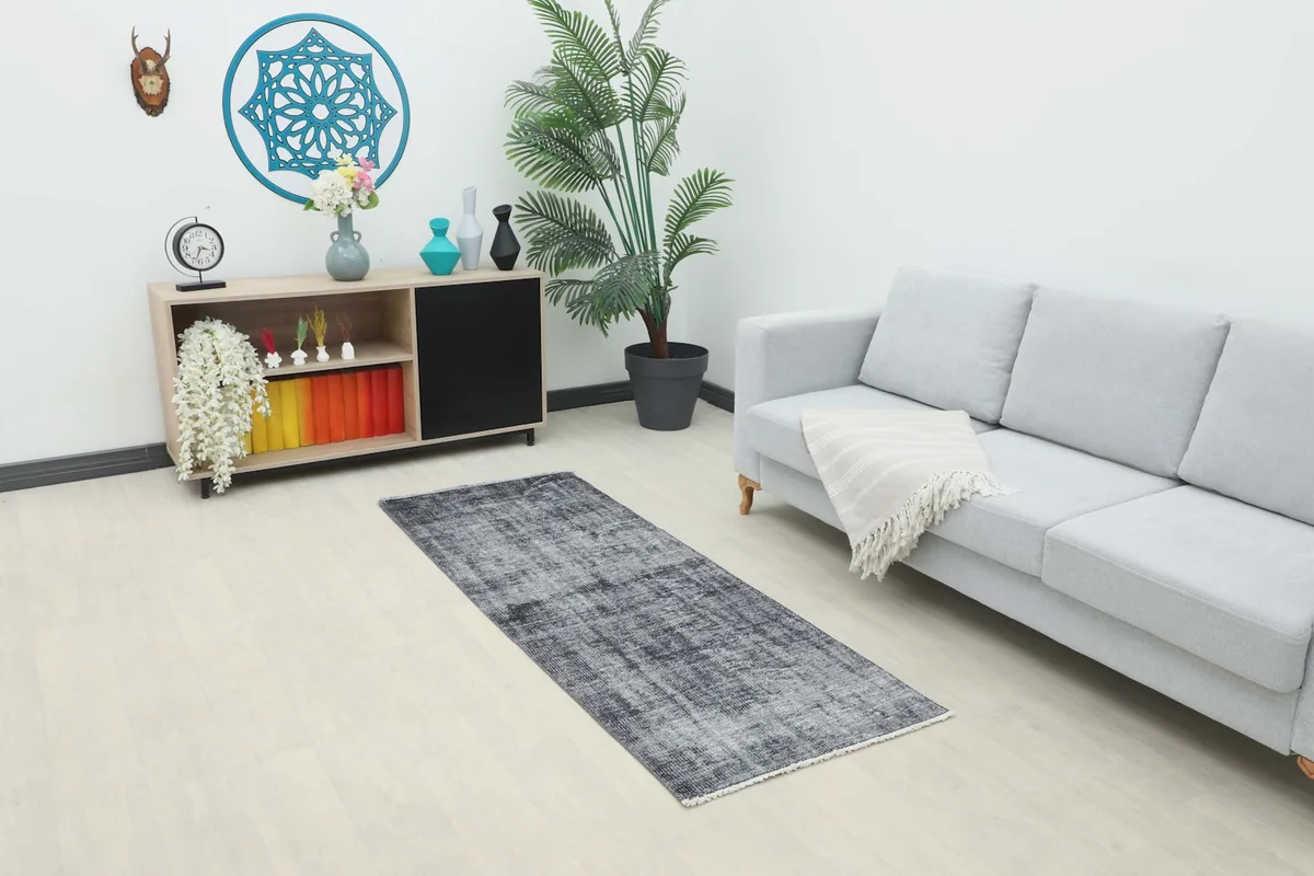 Vintage Anatolian runner rug displayed in a modern living room setting with a light gray sofa and wooden cabinet.