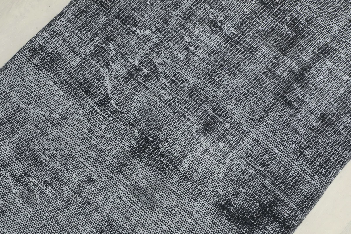 Detailed view of the distressed wool pile, showing the interplay of charcoal and gray threads in the runner.