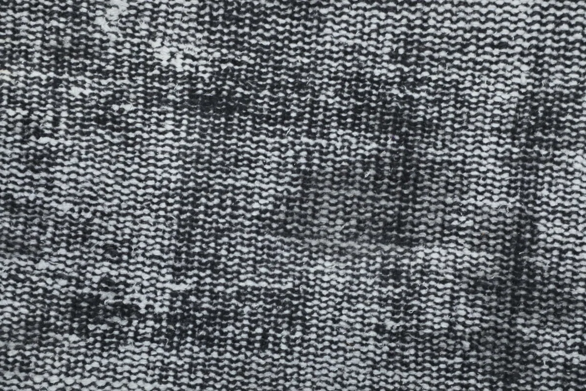 Macro shot of the hand-knotted low pile, revealing the intricate weaving and texture of the wool.