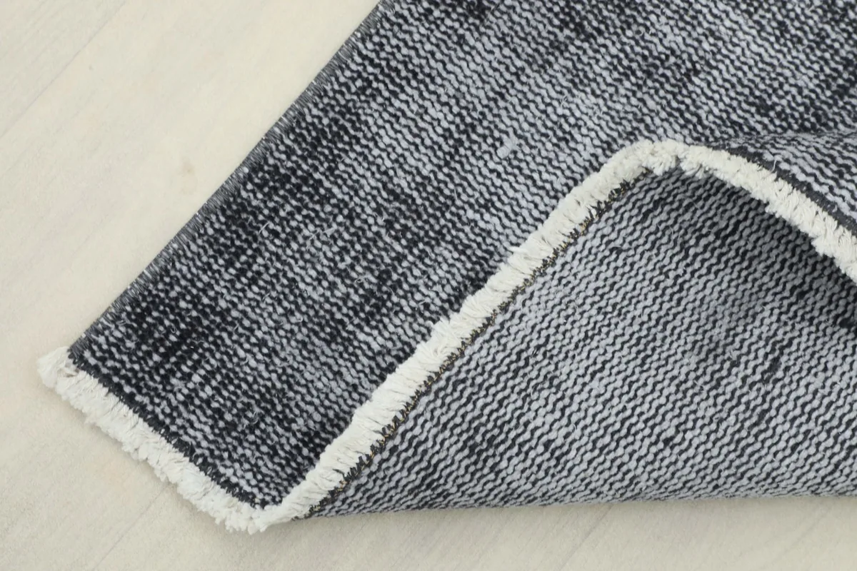 Corner of the runner rug folded to show the back, revealing the cotton foundation and hand-knotted construction.