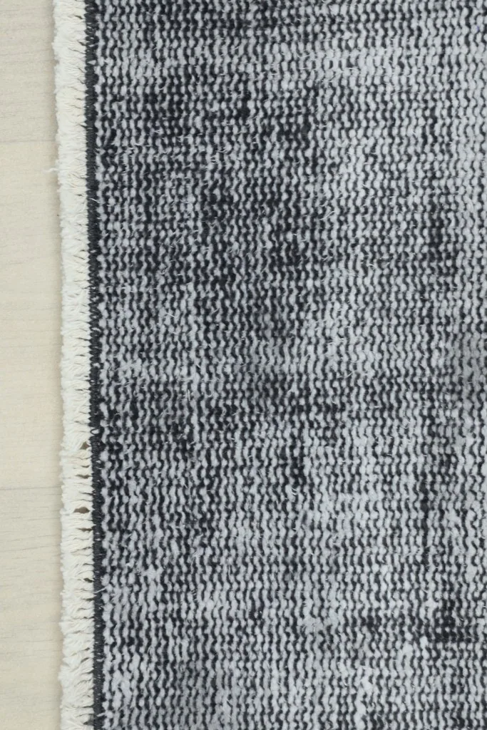 Close-up of the short, subtle fringe and the edge of the vintage runner rug.