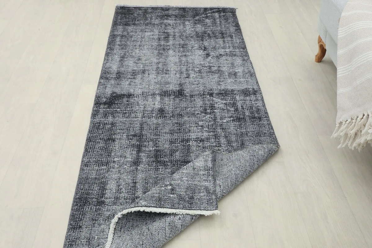 Runner rug partially folded back in a room setting, showing both the front pile and the reverse side.