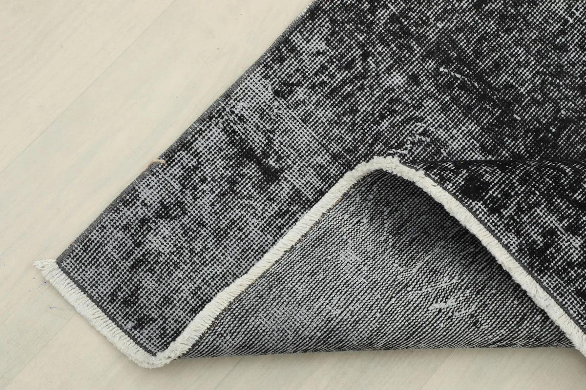 Corner of the rug folded back to show the cotton foundation and reverse side