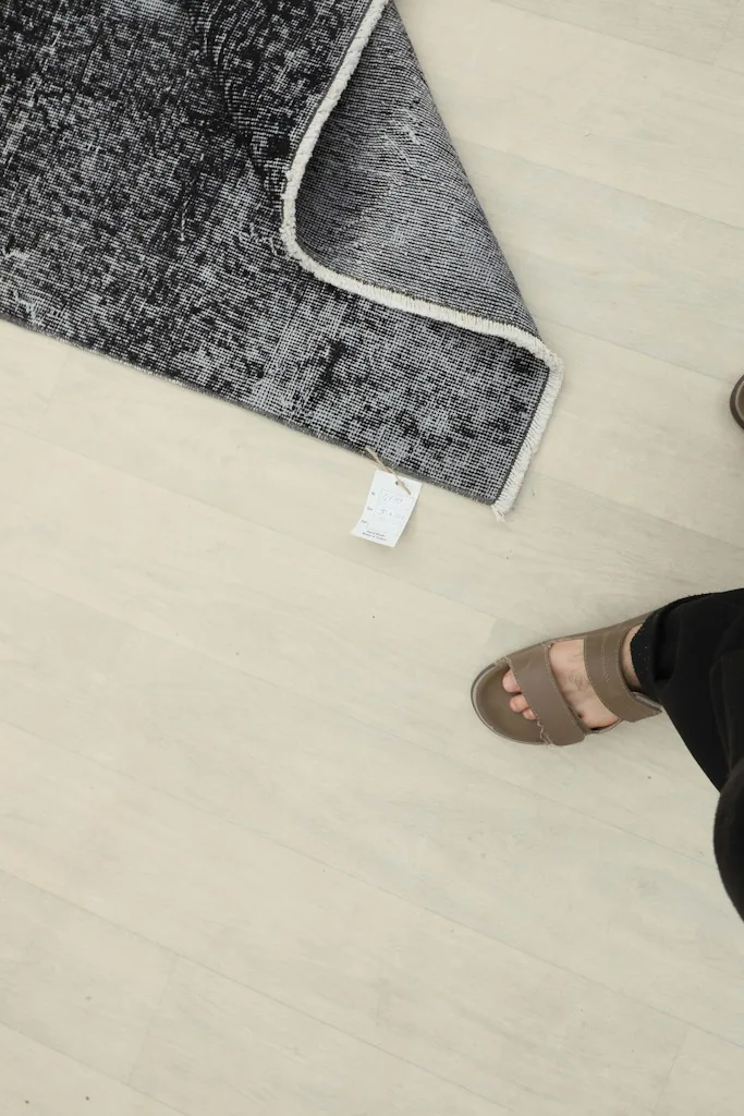 Overhead view of the rug's label and foundation, with a person's feet in the foreground