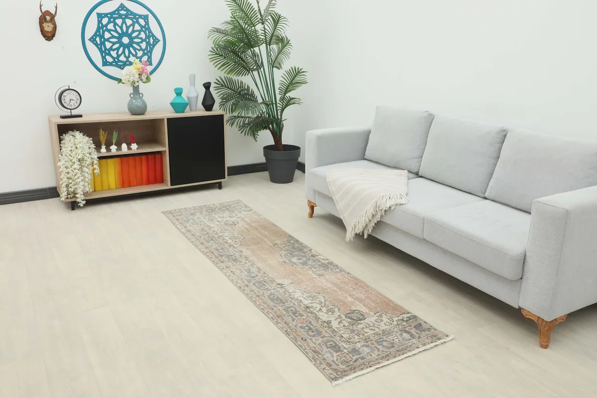 Vintage tan and blue runner rug placed in a modern living room setting with a light gray sofa