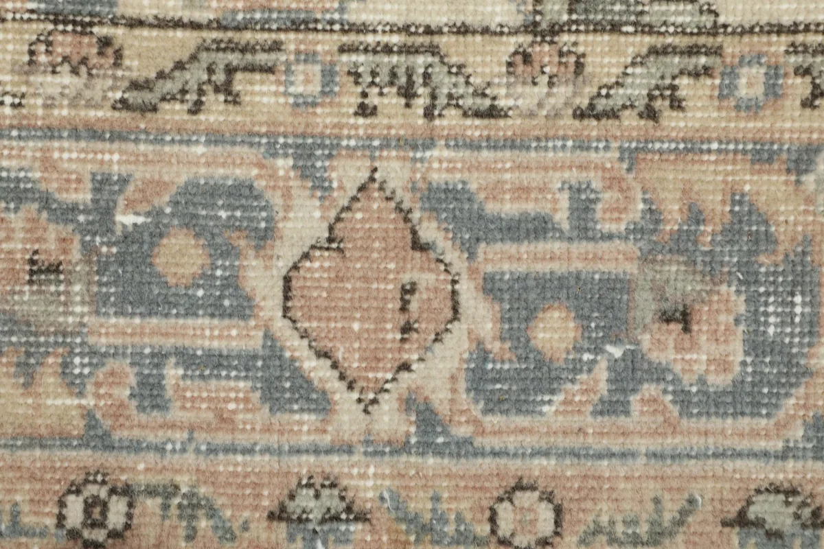 Extreme close-up of the low wool pile, showing the texture and faded blue and tan colors
