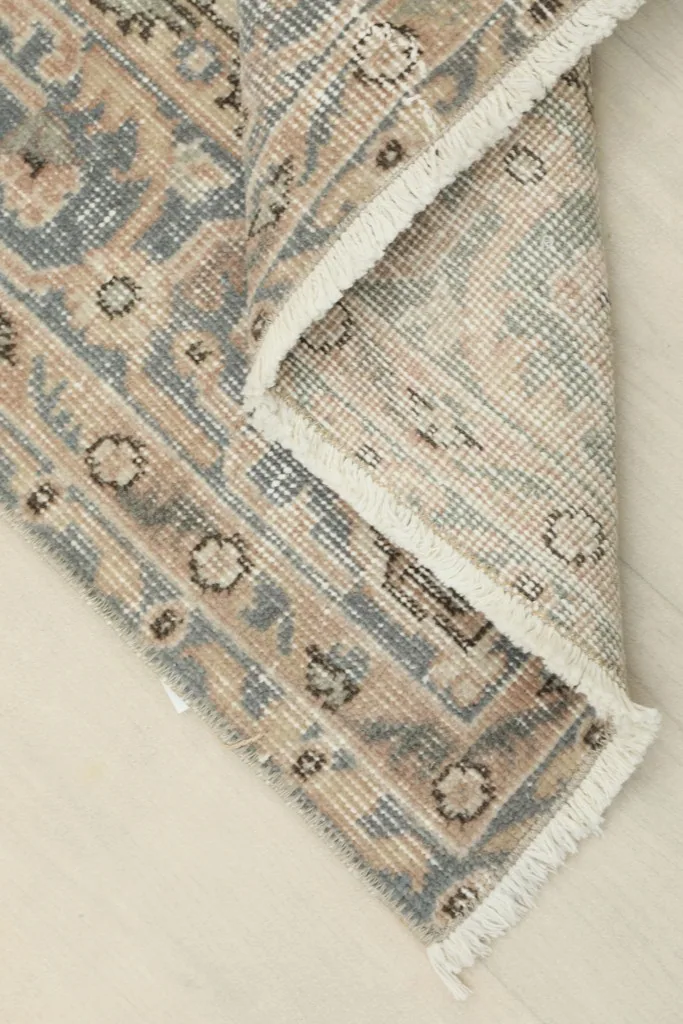 View of the rug folded to show the thickness and the backside of the hand-knotted wool