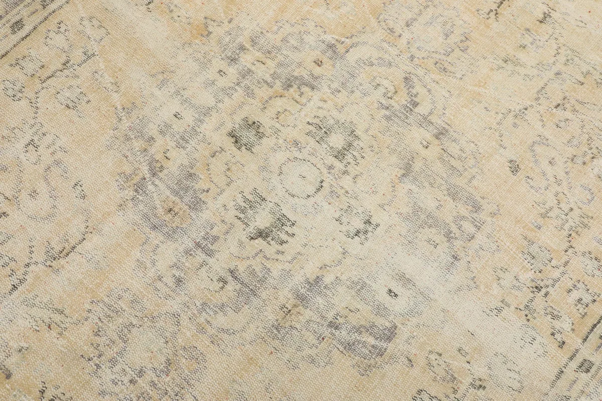 Detailed view of the central medallion and surrounding faded patterns on the vintage wool rug.