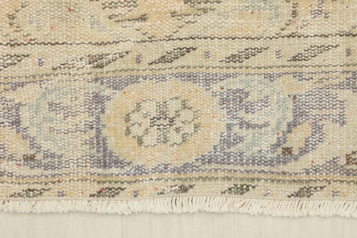 Detail of the rug's border design and short fringe, with visible blue and tan accents.
