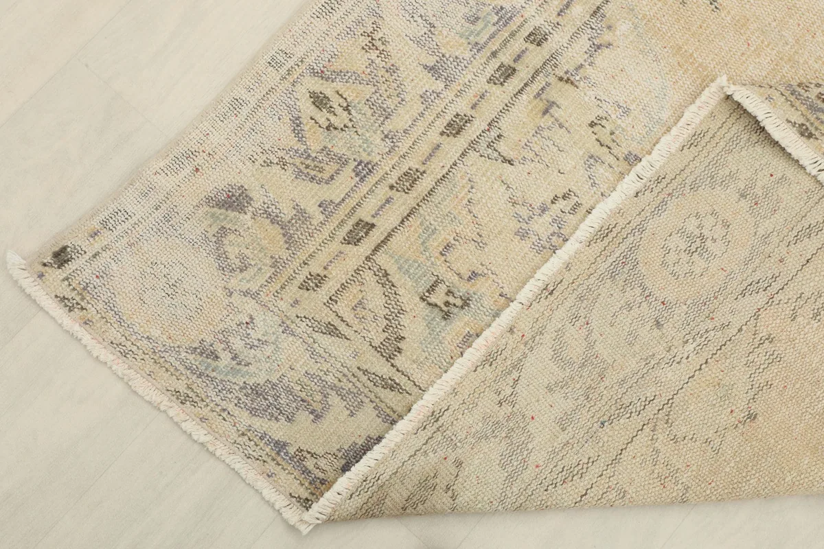 Corner of the rug folded back to reveal the cotton foundation and reverse side of the hand-knotting.