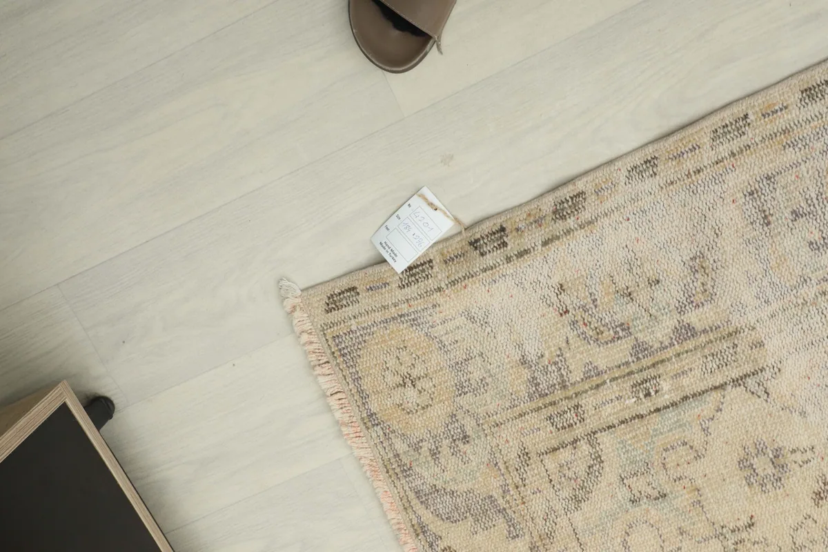 Overhead shot showing a corner of the rug with a measurement tag, indicating its size and vintage nature.
