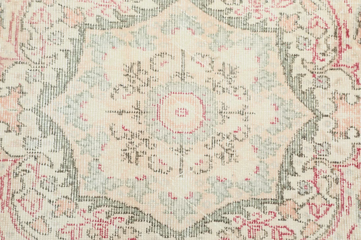 Close-up of the star-shaped motif within the central medallion, revealing gray and rose threads.