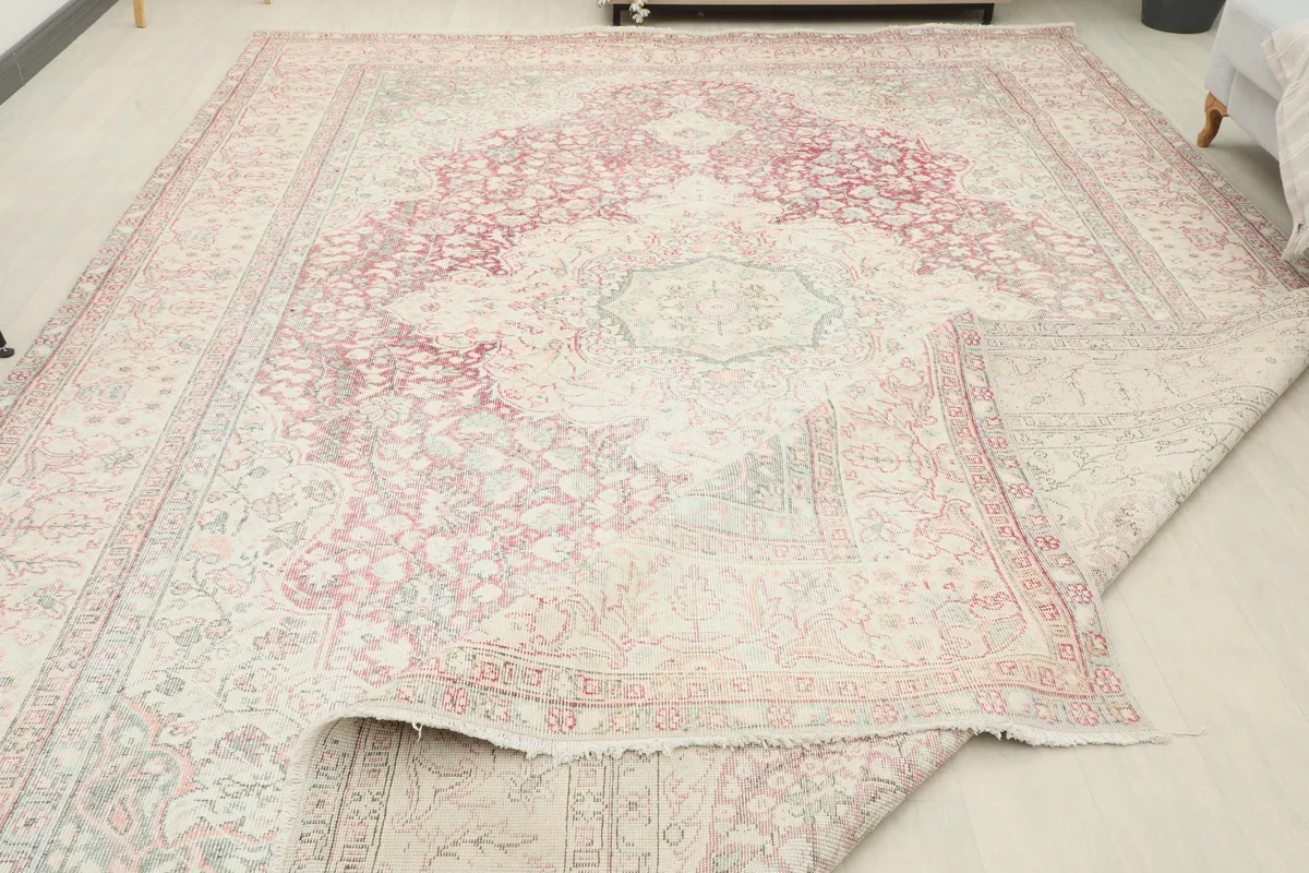 Rose Ivory Medallion Anatolian Rug partially folded, revealing the wool pile and cotton foundation.
