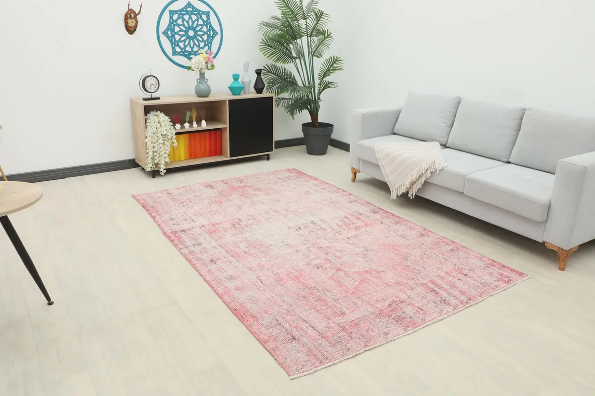 Rose faded vintage rug displayed in a living room setting with a light gray sofa and wooden cabinet.