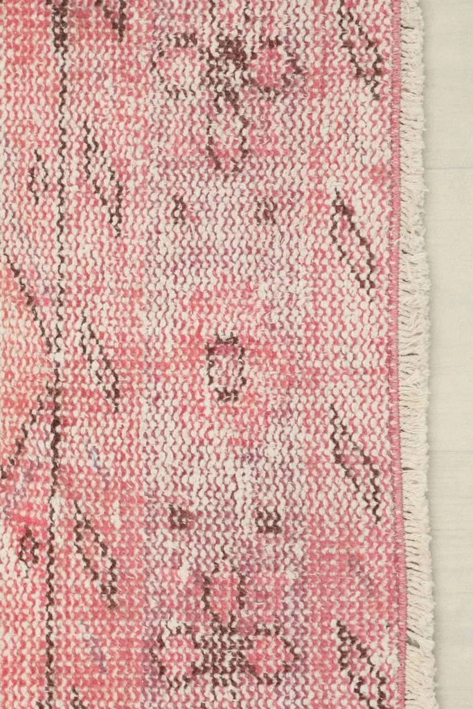 Detail of the rug's edge, showcasing the subtle border design and the short, natural fringe.