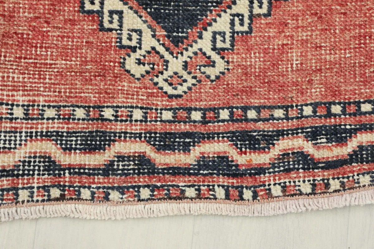 Close-up of the short, natural fringe and the patterned border at one end of the vintage rug