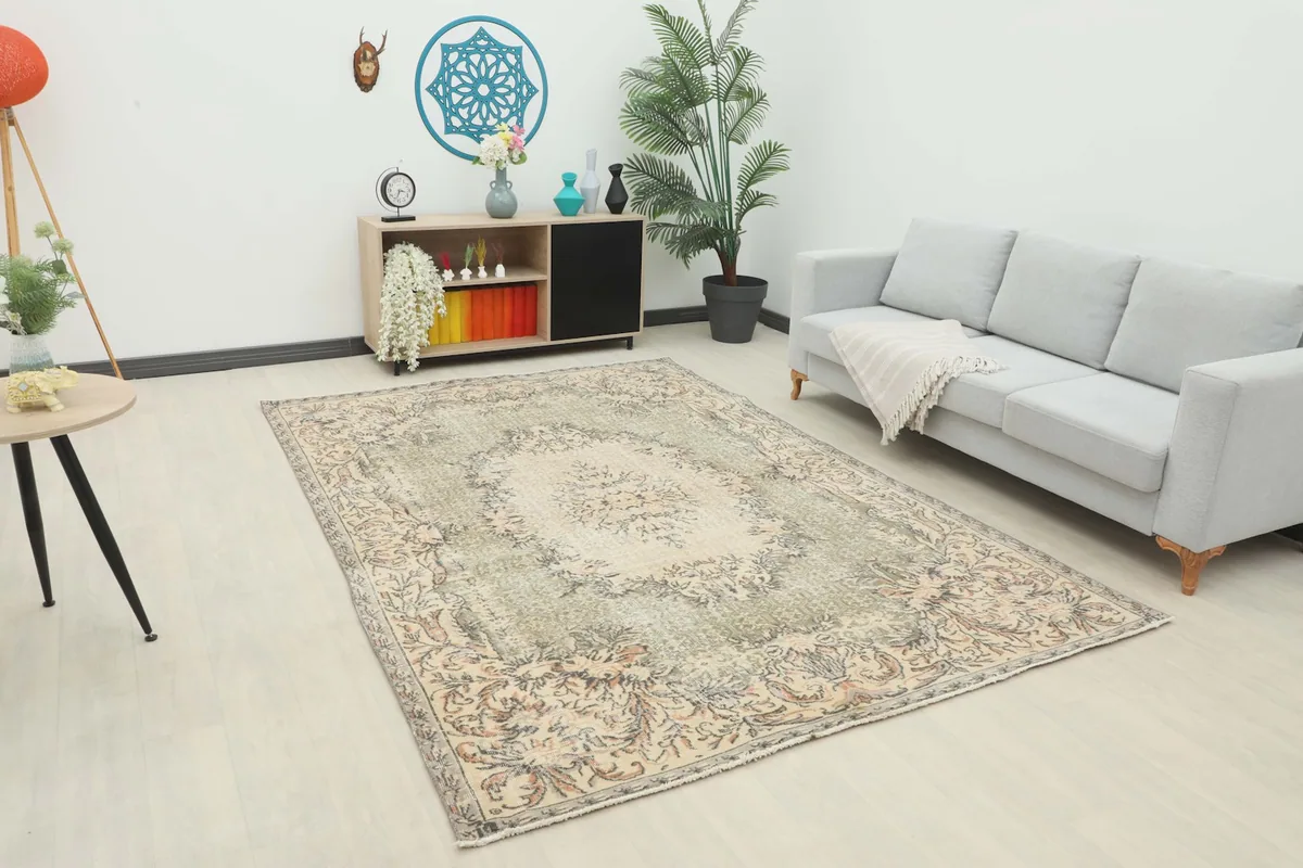 Vintage beige and olive rug displayed in a bright living room setting with a light gray sofa.