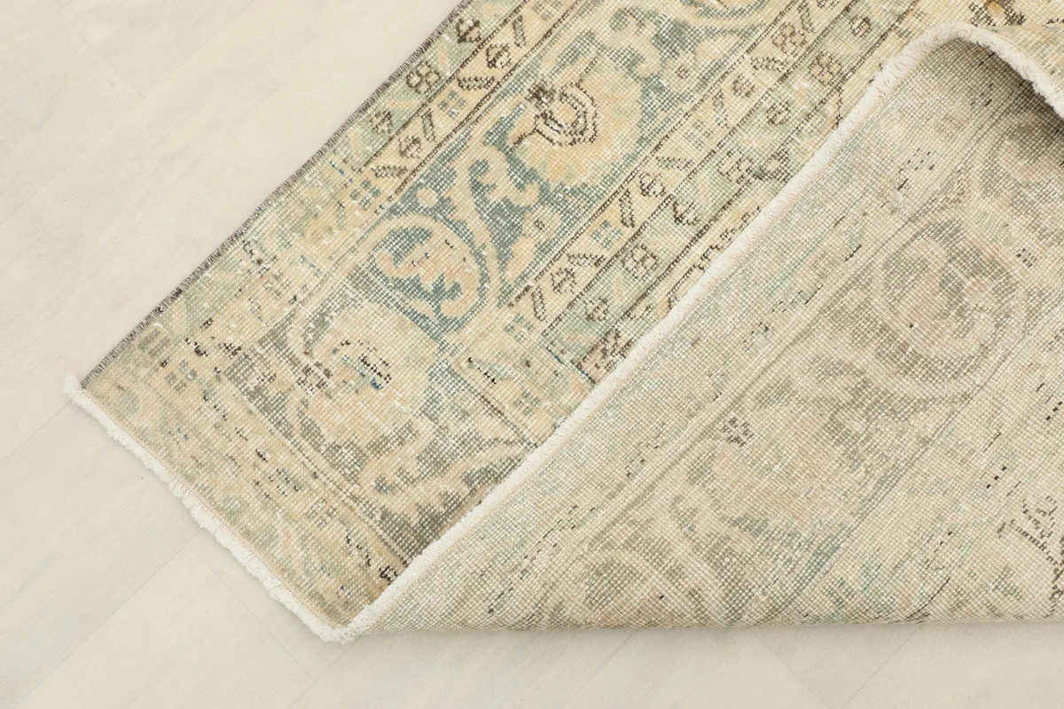 Corner of the rug folded back to show the cotton foundation and the reverse side of the knots