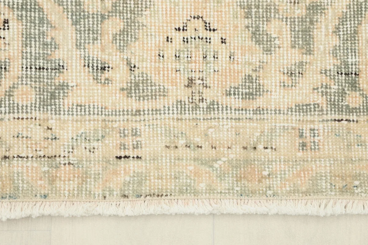 Detail of the rug's edge and short, natural cream fringe, showing the hand-knotted construction